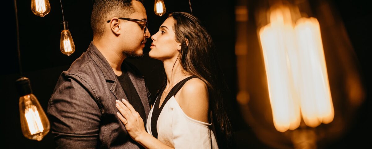 Casal se beijando embaixo de lâmpadas