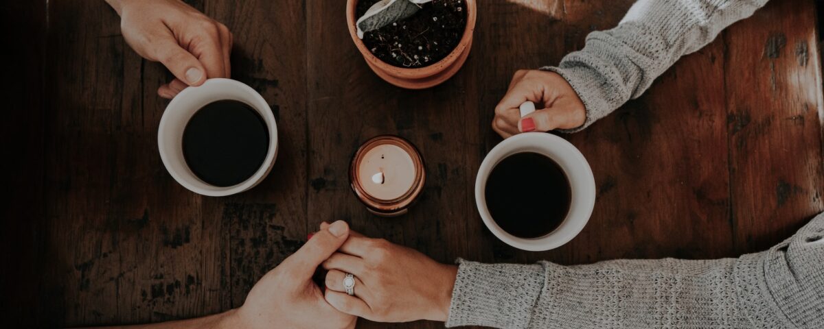 Casal segurando mãos enquanto toma café