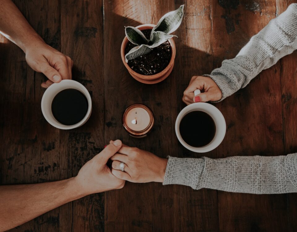 Casal segurando mãos enquanto toma café